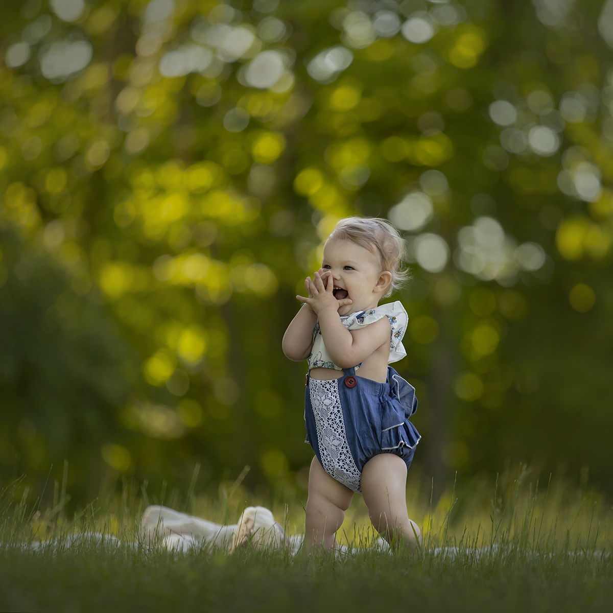 Toddler in blue romper in grassy field