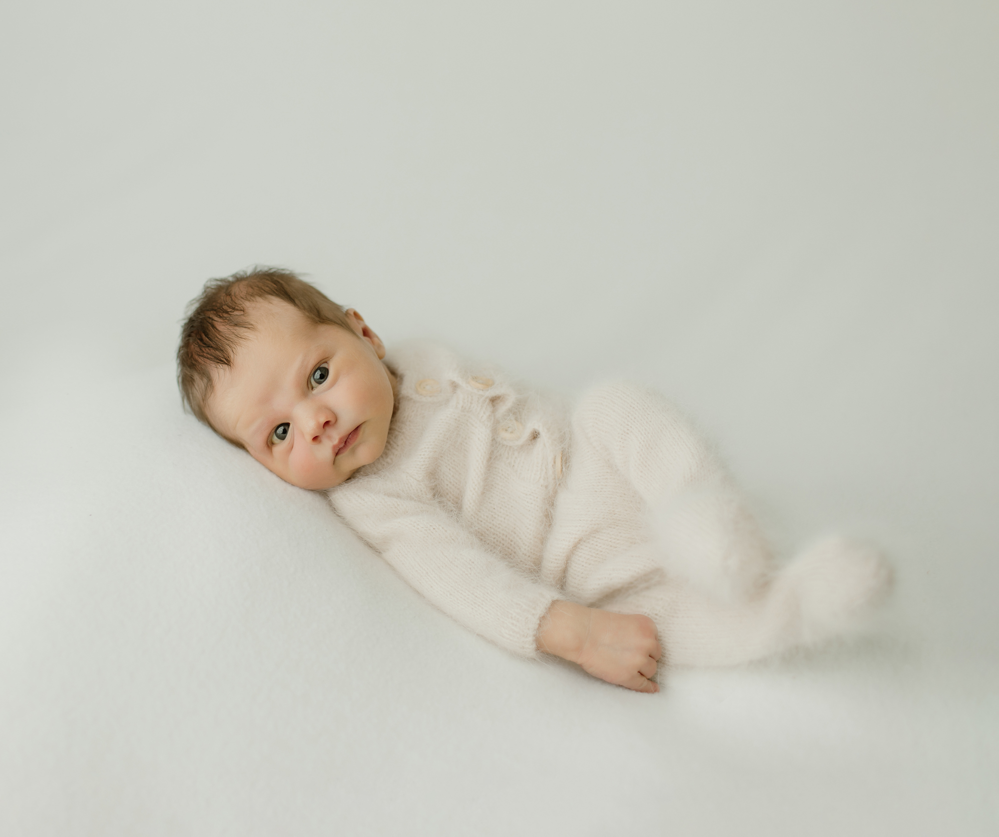 Newborn portrait of baby in fuzzy white pajamas