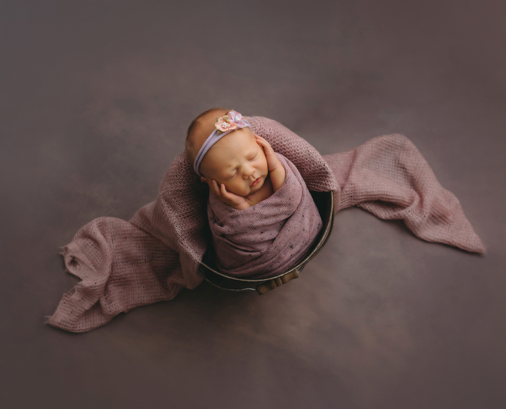 Newborn portrait of baby in pink wrap and bucket