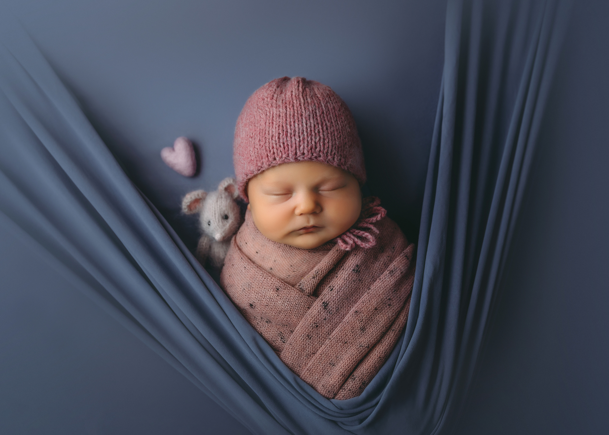 Newborn portrait of baby in pink wrap and bonnet