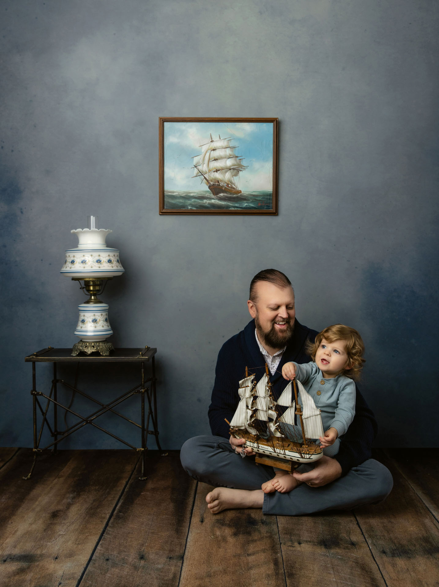 Portrait of dad playing with toddler and model ship on floor