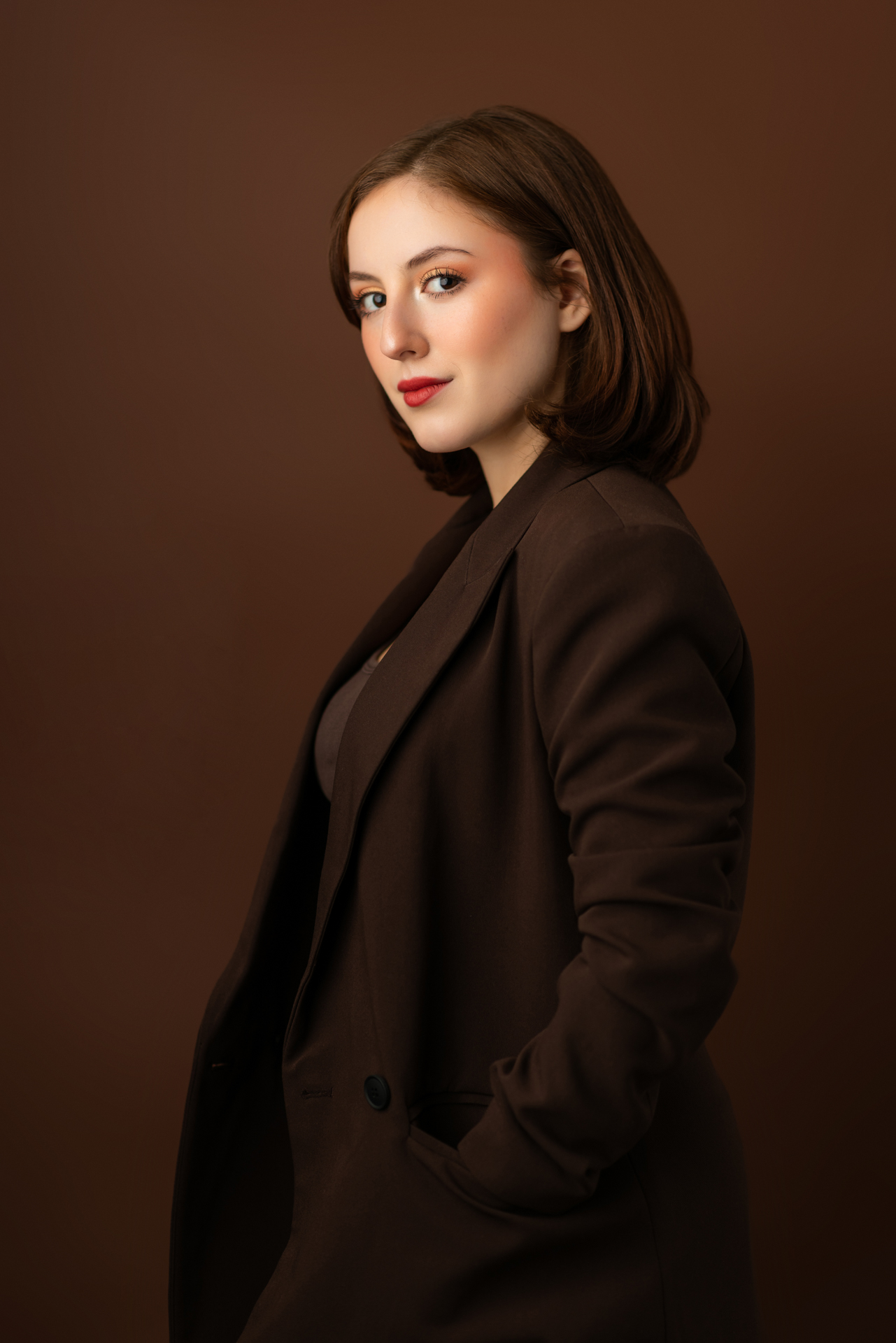 Professional musician headshot of young woman in brown blazer on matching brown background